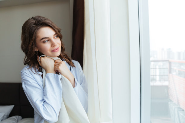 一个快乐的女人拉开窗帘的画像图片下载