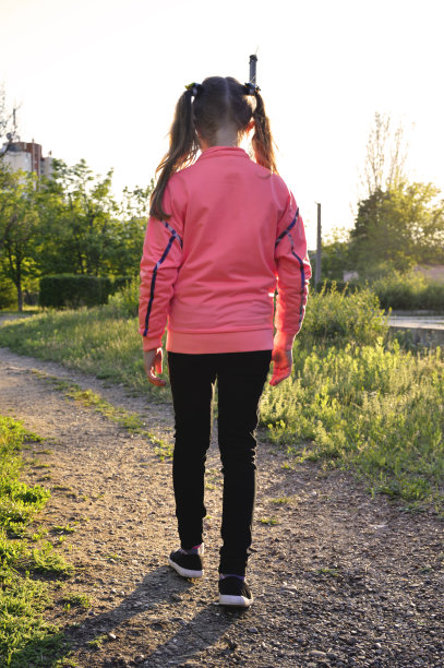 长发女孩在日落时分走在田间小路上图片下载