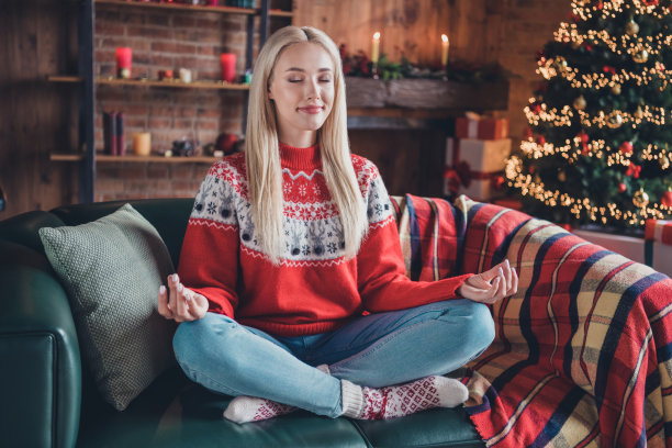 迷人的梦幻欢快的女孩肖像坐在沙发上，穿着节日套头衫，在现代loft工业风格的室内冥想图片下载