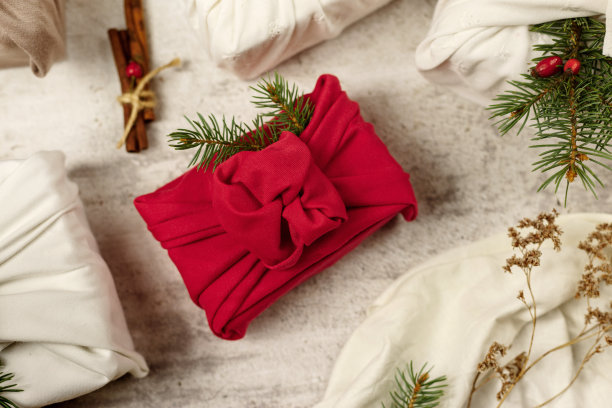 日本裹布糠木，传统上用来运送礼物。红白相间的布料上点缀着绿色的冷杉、松果、肉桂和玫瑰果。图片下载