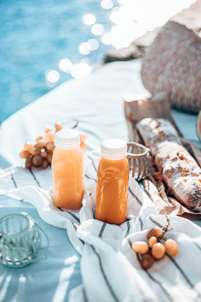 在阳光明媚的日子里，码头上的塑料瓶新鲜榨的果汁。海上野餐的食物图片下载