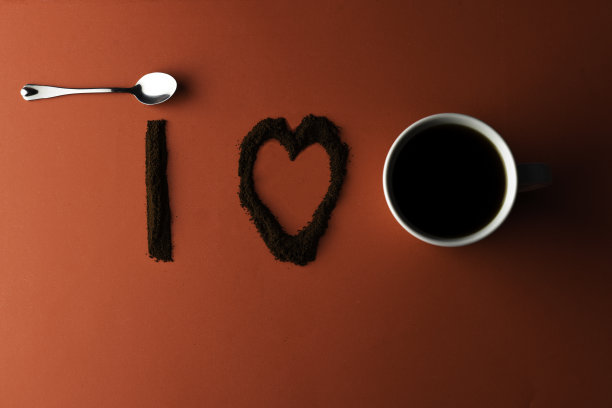 用咖啡豆写的“我”加上用咖啡豆和白色咖啡杯写的“心的符号”。红色的背景。图片下载