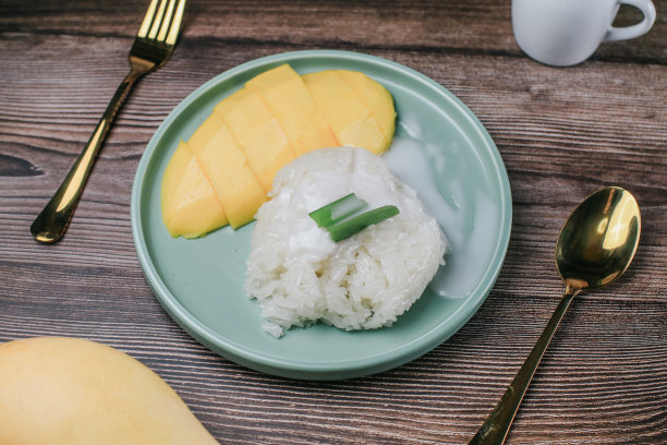 美味的芒果糯米饭和椰奶放在木桌上。泰国流行的传统甜点。图片下载