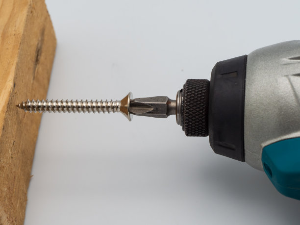 在实木工作台上，木匠使用电动螺丝刀。图片下载