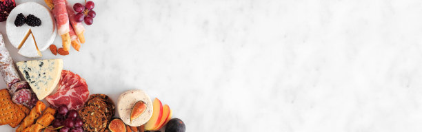 在白色大理石旗帜的背景上，有各式各样的奶酪和肉类开胃菜图片下载