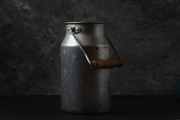 旧牛奶铝罐在一个黑暗的背景图片下载
