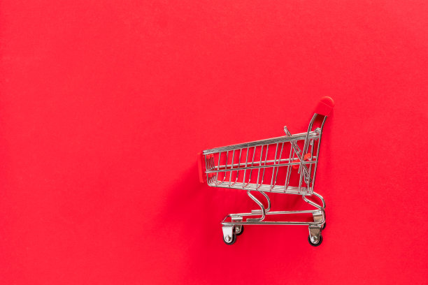 红色背景上有礼品盒的杂货店购物车。图片下载