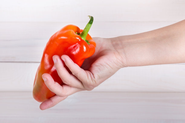 保加利亚甜椒在白色木制背景上人手。图片下载