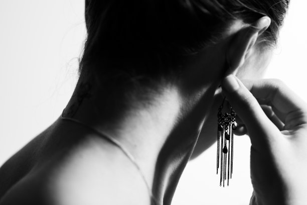 一个女人在聚会前试耳环。黑白照片。图片下载