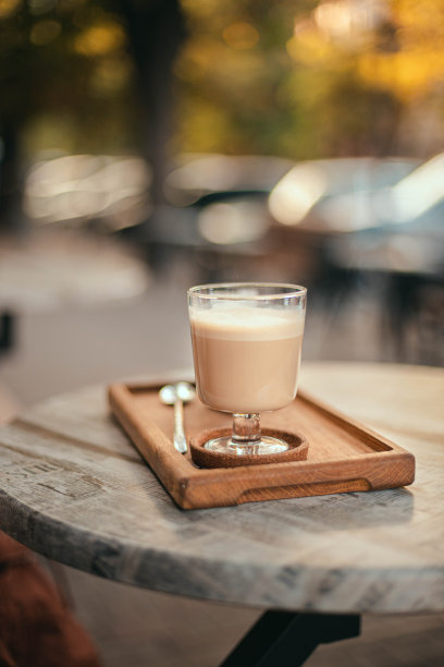 拿铁或加牛奶的咖啡放在公园的街边桌子上的木托盘上。垂直取向照片图片下载