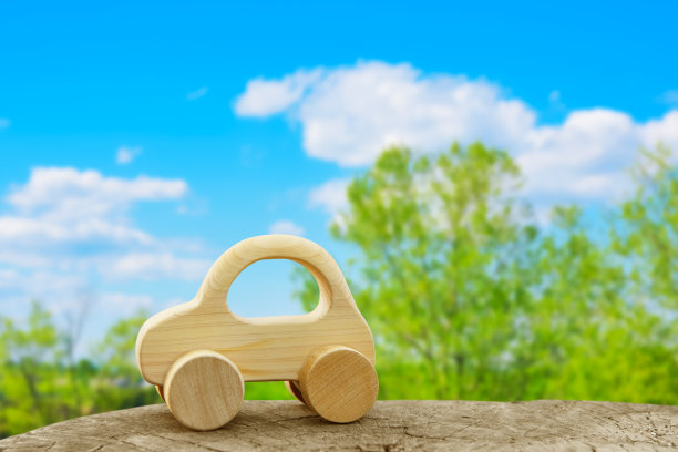 木制玩具车。新鲜的绿色树木背景。图片下载