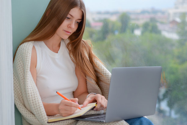 年轻的女学生在笔记本电脑上做作业。在线学习图片下载