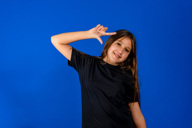 白人小女孩的肖像，用食指指着头，在蓝色的背景上孤立地看着旁边图片下载
