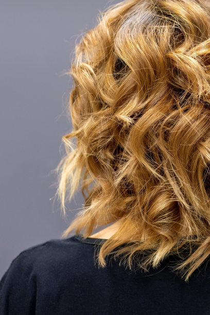 深色背景上，站着一位留着长长的棕色卷发的女子。图片下载