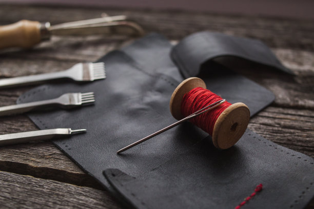 皮革。缝纫一个钱包。皮革的工作。缝纫袋，钱包，手包的工具。手工缝制产品。皮革制品的制造。图片下载