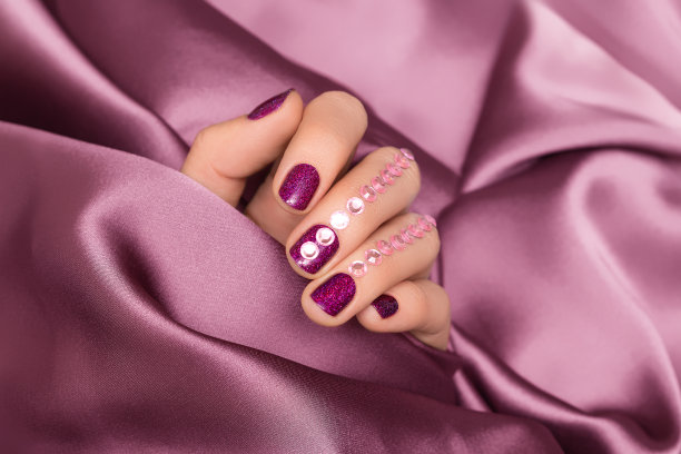 女性手与粉红色指甲设计。亮粉色指甲油指甲油与宝石指甲艺术。粉色指甲的模特手。图片下载