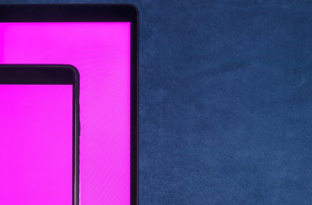 一台紫色空白屏幕的智能手机放在蓝色天鹅绒背景下的平板电脑屏幕上。图片下载