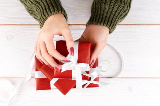 女孩的手打开白色背景下的圣诞节、生日或情人节红色礼物图片下载