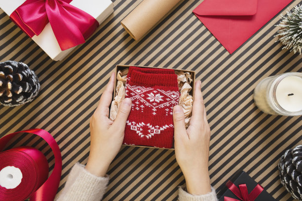 年轻女子折叠派对袜子在工艺礼品盒的条纹背景。图片下载