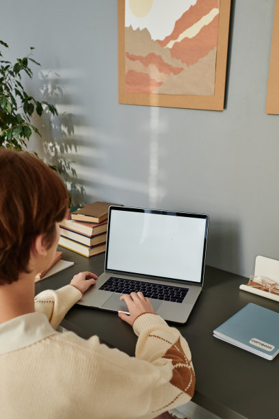 穿毛衣的红发女学生坐在桌子旁使用笔记本电脑图片下载