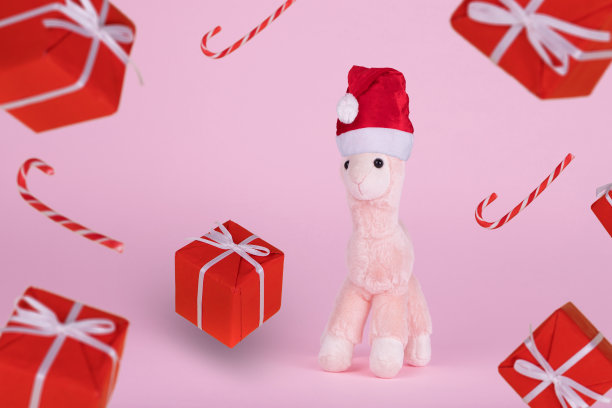 可爱的玩具羊驼戴着圣诞帽，盒子里装着圣诞礼物。图片下载