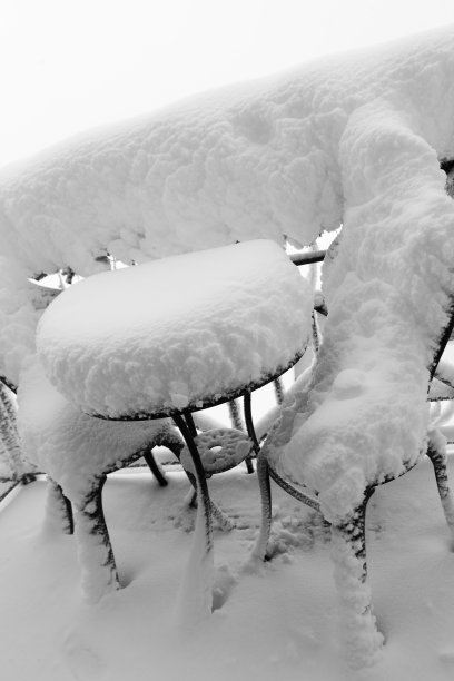 暴风雪过后，露台上的花园家具上积了大量的雪。由大雪、霜冻和冻雨引起的自然灾害。图片下载
