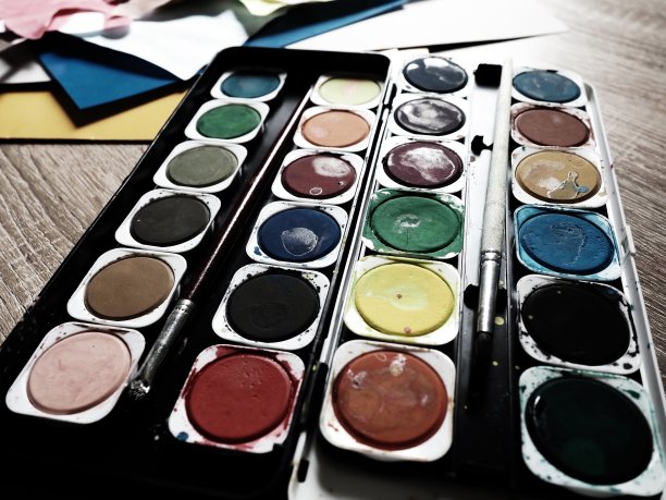 一套不同颜色的水彩画。色彩鲜艳的圆形容器。绘画课的工具和劳动。彩色的纸。红色，蓝色，黄色，绿色。图片下载