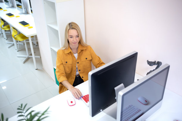 一个年轻的女人坐在办公室的电脑前。远程工作的概念图片下载