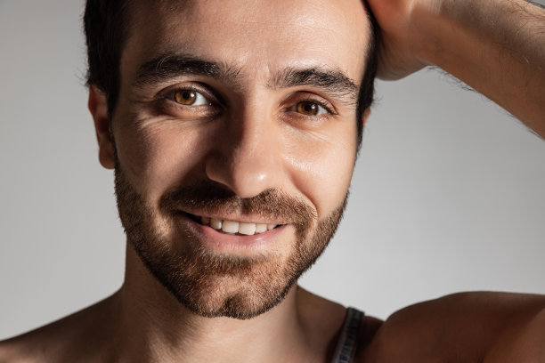 特写的年轻英俊的胡子赤膊男子孤立在灰色的工作室背景。自然美景图片下载