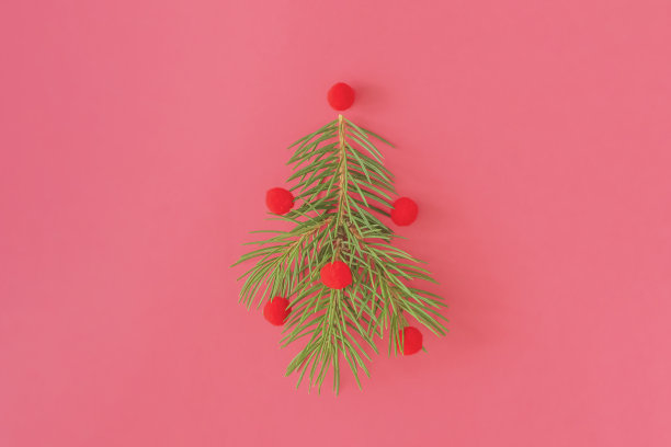圣诞树在紫色粉红色的背景上，用红色的毛毡球装饰。杉树的树枝，做成新年树的形状。圣诞节和新年的概念图片下载