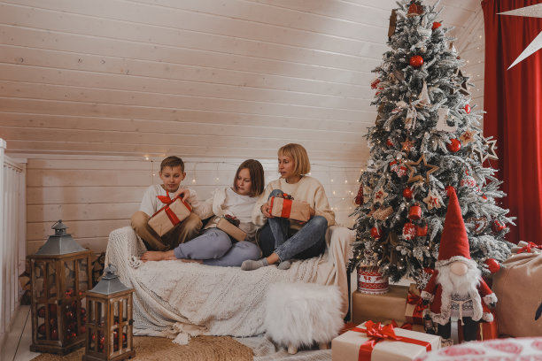 家人在平安夜。孩子们打开礼物。孩子们在圣诞树下拿着礼品盒。新年装饰的房间。温暖舒适的冬夜在家。图片下载