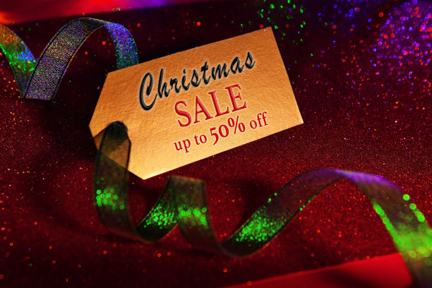 金色标签与文字-圣诞节销售高达50折，明亮的绿色丝带，明亮的节日豪华闪亮的红色背景。图片下载