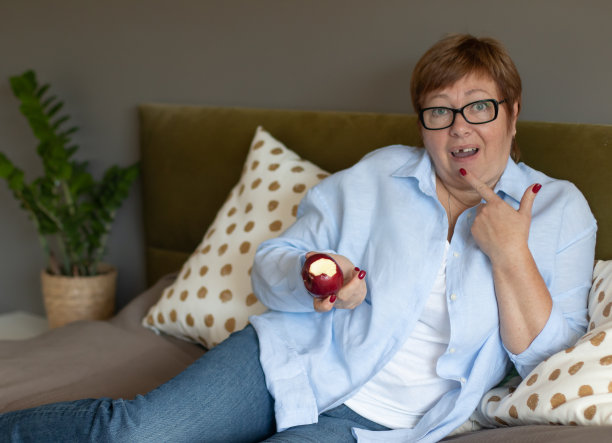 一位上了年纪的妇女咬了一口苹果，把牙齿弄坏了。牙科和牙科问题的概念图片下载