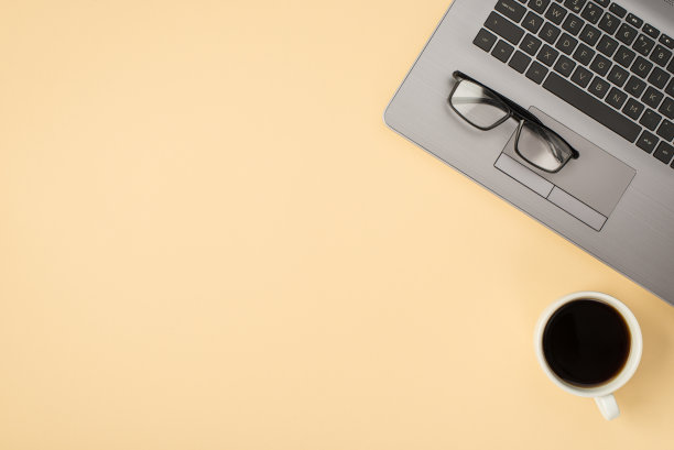 上面的照片灰色笔记本电脑眼镜和咖啡杯孤立在米色背景与空白图片下载