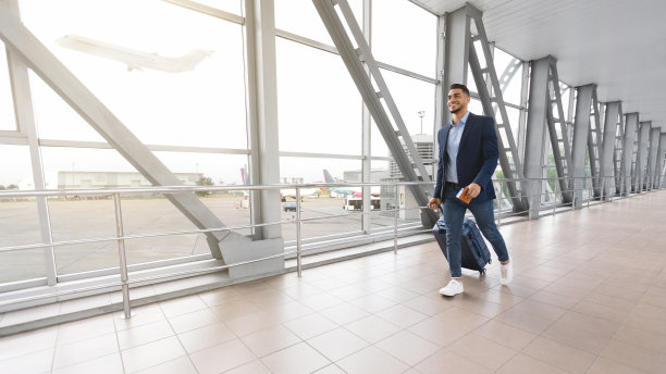 准备旅行。微笑英俊的中东男子在机场提着行李箱图片下载