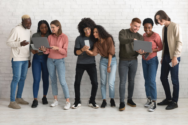 快乐的多种族千禧一代在一起时使用电子产品图片下载