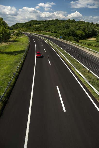 那辆红色小汽车在新公路上行驶。图片下载