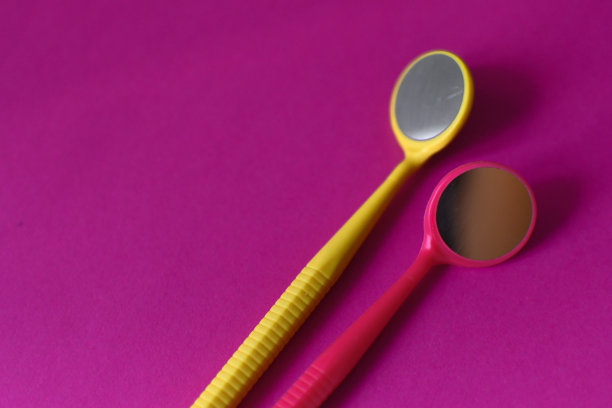 两个牙科镜子在粉红色背景上的特写。本空间图片下载