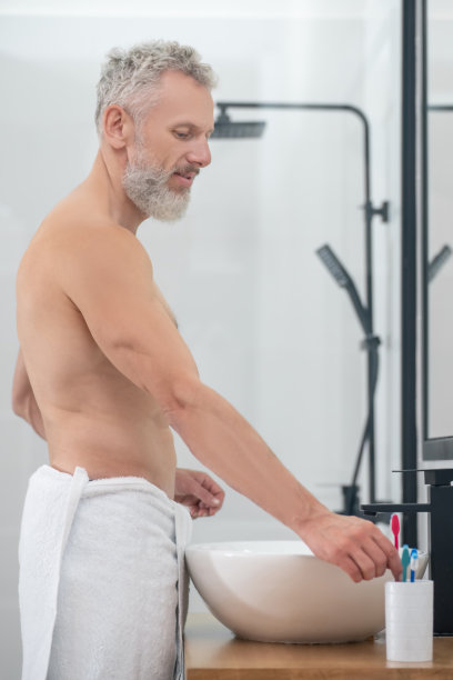 赤裸上身的男人在浴室拿牙刷图片下载