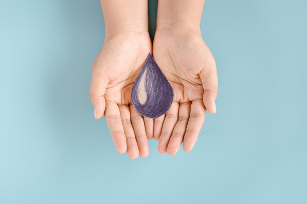 水世界企业社会责任:可持续生活方式理念，节约用水，保护环境，实现资源可持续发展。女性手拿水滴符号在孤立的蓝色背景。可持续性的生活图片下载