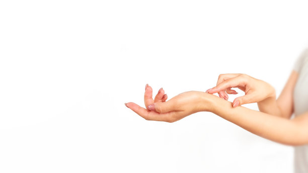 女性的手在手上涂抹乳液。在白色背景上隔离。Deporsonalization。图片下载