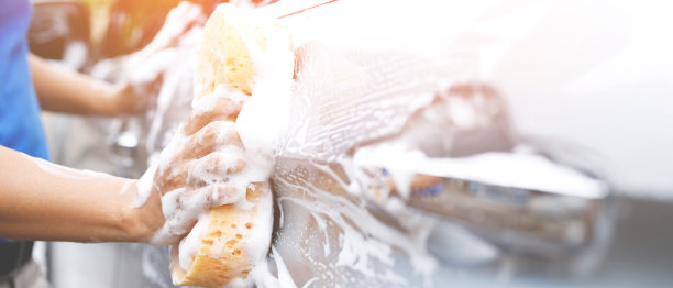 人们用工人的手拿着黄色的海绵和泡沫洗刷窗来洗车。概念车清洗干净。留下写信息的空间。图片下载