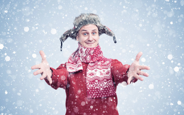 穿着红色毛衣、戴着围巾、戴着帽子的快乐男人伸出双手，在冬日和雪天里欣喜不已图片下载