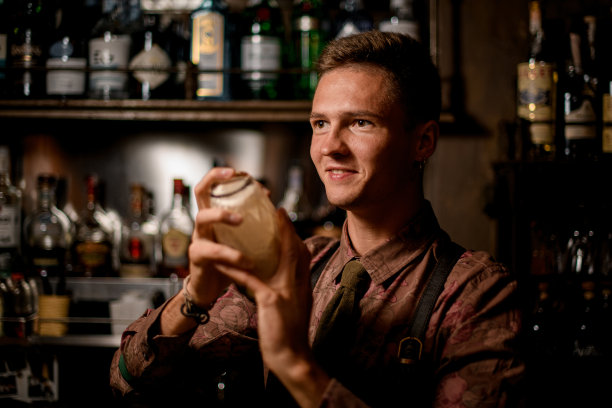 年轻的男调酒师面带微笑，手持摇酒杯图片下载