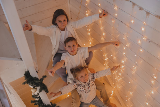 孩子们在圣诞装饰的楼梯上玩耍，在新年装饰的房子里，家庭，冬季假期和人们的概念图片下载