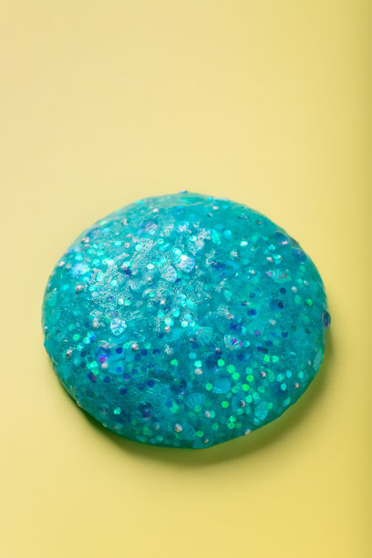 蓝色闪光粘液在黄色的背景。有趣的感觉玩具图片下载