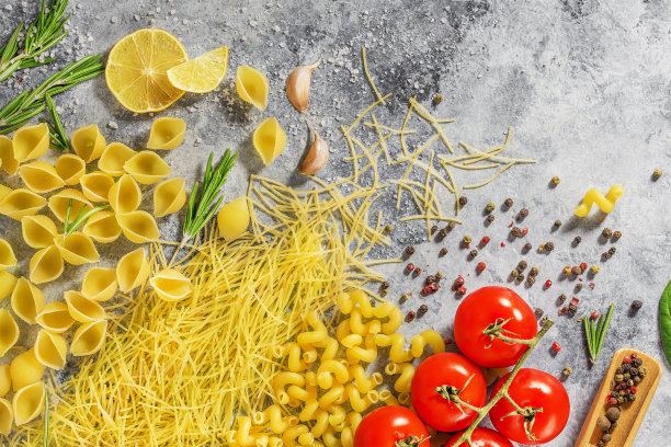 黑色背景的桌子上放着意大利面、红番茄、大蒜和香草图片下载