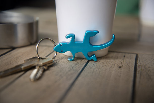 咖啡杯的地板上放着一个蓝色蜥蜴玩具做的钥匙链。桌子上有一个烟灰缸图片下载