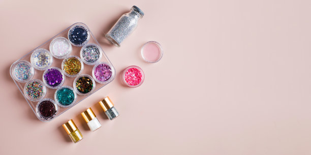 收藏的瓶子上有彩色的闪光和亮片装饰在浅粉色的背景上，俯视图。本空间图片下载