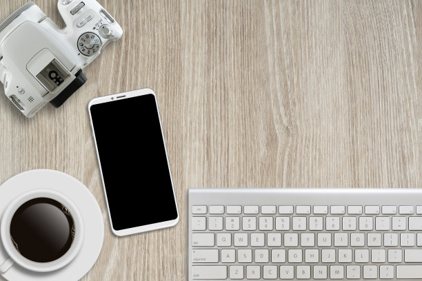 家庭办公桌面的顶视图，木桌上的黑屏智能手机。图片下载
